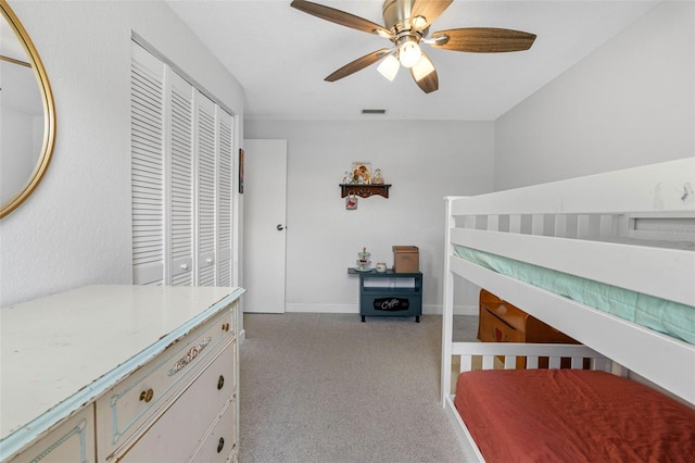 bedroom with a closet, light colored carpet, visible vents, a ceiling fan, and baseboards