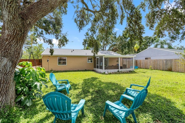 back of house with a sunroom, a fenced backyard, a lawn, and stucco siding