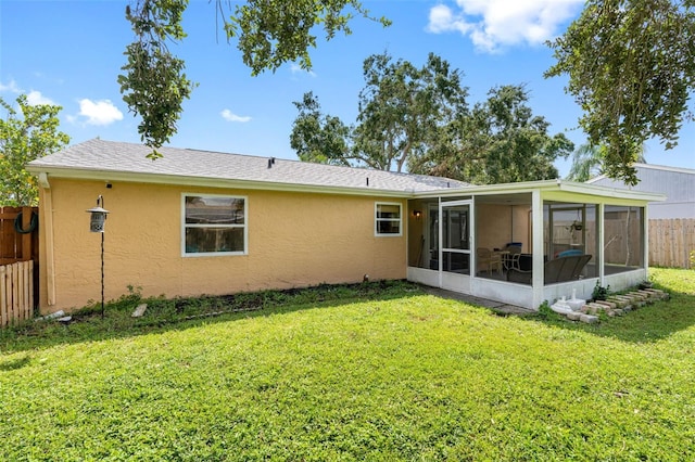 back of property featuring a sunroom, fence, a lawn, and stucco siding