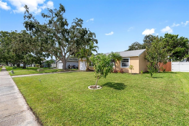 view of front of house with a front lawn, fence, an attached garage, and stucco siding