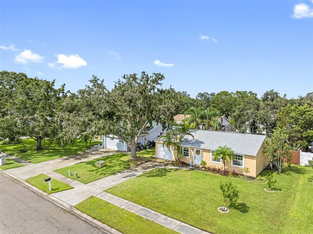 single story home featuring a garage, concrete driveway, a front lawn, and stucco siding