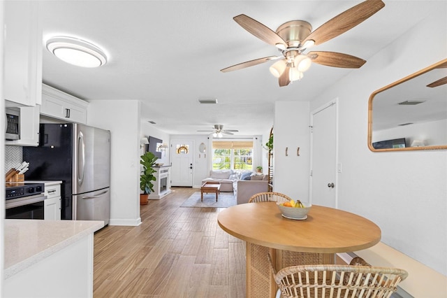 dining room featuring light wood-type flooring, baseboards, visible vents, and a ceiling fan