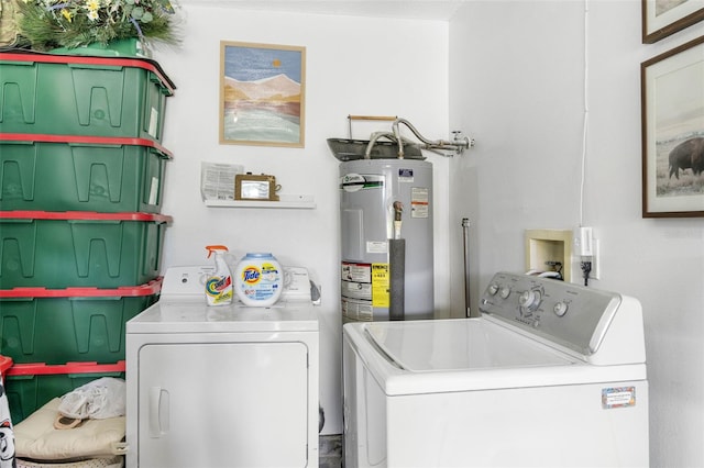 clothes washing area featuring laundry area, electric water heater, and washing machine and clothes dryer