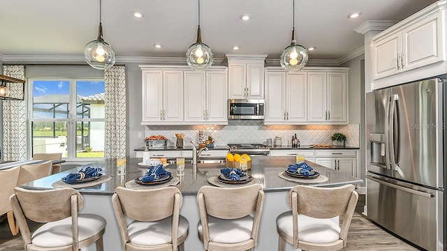 kitchen with pendant lighting, decorative backsplash, white cabinetry, and appliances with stainless steel finishes