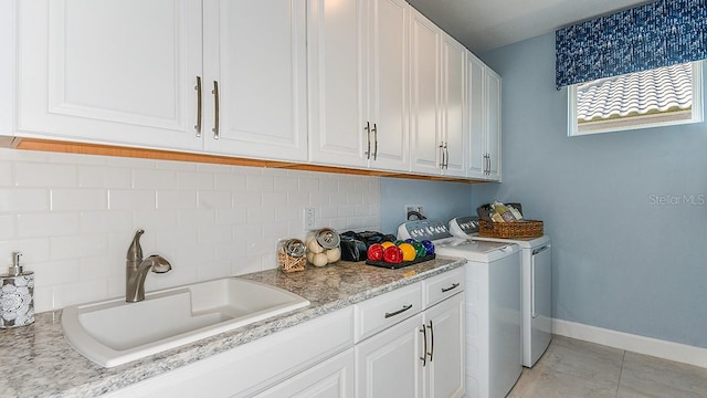 laundry room featuring washing machine and clothes dryer, sink, light tile patterned floors, and cabinets