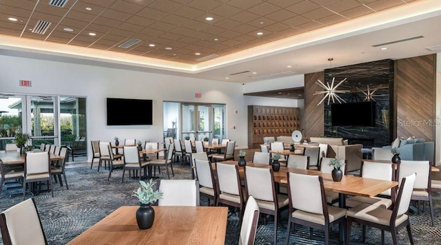 dining space featuring a tray ceiling, wooden walls, a towering ceiling, and a healthy amount of sunlight