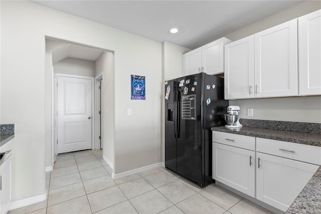 kitchen with white cabinetry, light tile patterned flooring, and black fridge