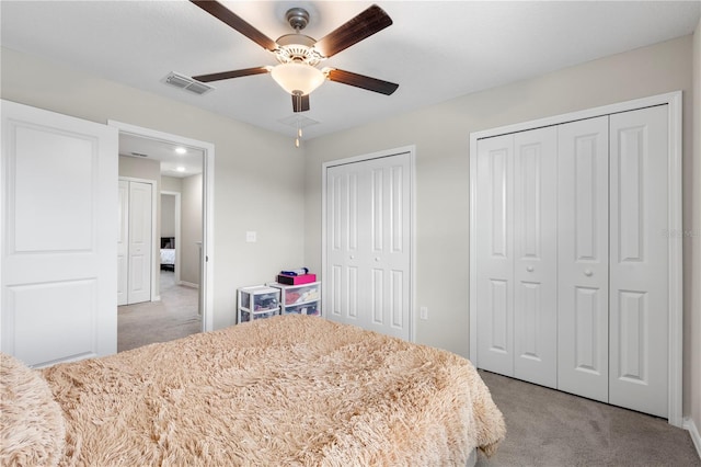 carpeted bedroom with two closets and ceiling fan