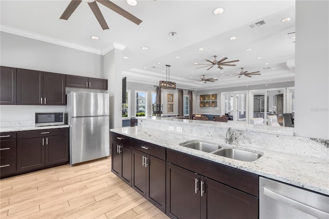 kitchen featuring a raised ceiling, appliances with stainless steel finishes, pendant lighting, light hardwood / wood-style floors, and sink