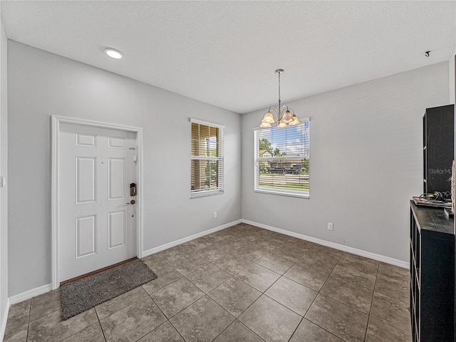 unfurnished dining area featuring a notable chandelier, a textured ceiling, and tile patterned flooring