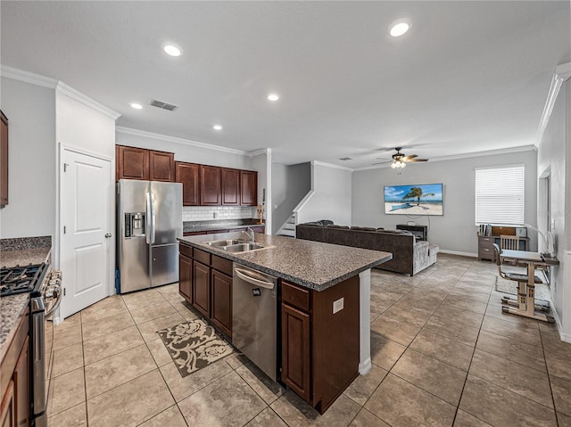 kitchen featuring ornamental molding, stainless steel appliances, sink, and an island with sink