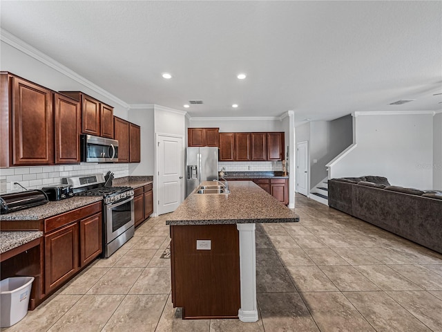 kitchen with tasteful backsplash, a breakfast bar area, appliances with stainless steel finishes, a kitchen island with sink, and ornamental molding