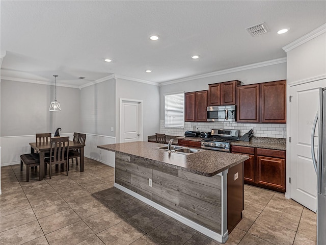 kitchen featuring sink, stainless steel appliances, decorative light fixtures, ornamental molding, and a kitchen island with sink