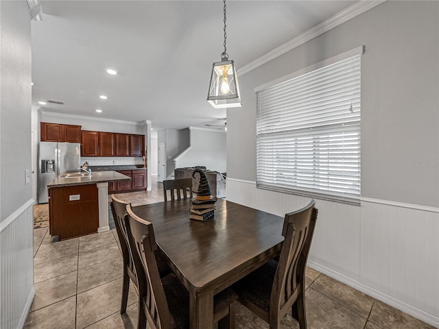 tiled dining room with sink and crown molding