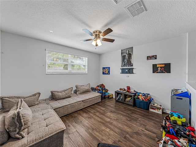 living room featuring ceiling fan, a textured ceiling, and dark hardwood / wood-style flooring