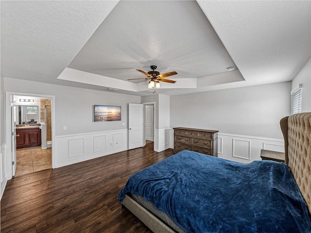 bedroom featuring connected bathroom, ceiling fan, multiple windows, and dark hardwood / wood-style flooring