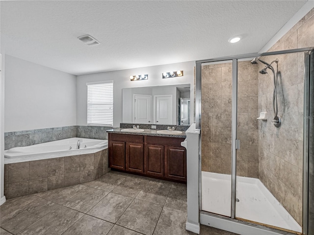 bathroom featuring vanity, independent shower and bath, a textured ceiling, and tile patterned flooring