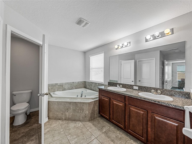 bathroom featuring toilet, a textured ceiling, vanity, and tiled bath