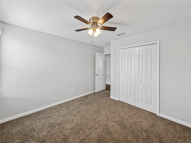 unfurnished bedroom with a closet, ceiling fan, a textured ceiling, and dark colored carpet