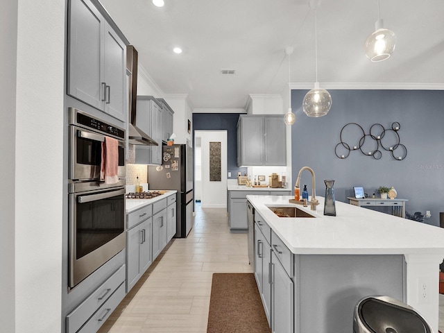 kitchen featuring appliances with stainless steel finishes, sink, decorative light fixtures, gray cabinets, and a breakfast bar