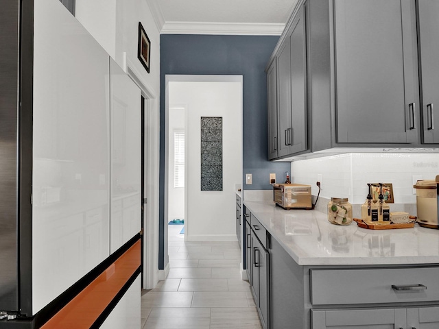 kitchen featuring light stone counters, ornamental molding, light tile patterned floors, and gray cabinets