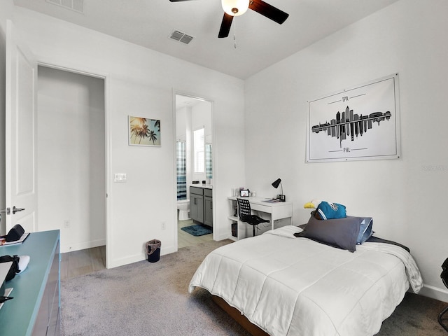 bedroom featuring ensuite bath, light wood-type flooring, and ceiling fan