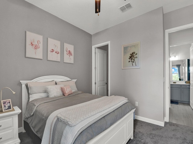 bedroom with ensuite bathroom, dark colored carpet, and ceiling fan