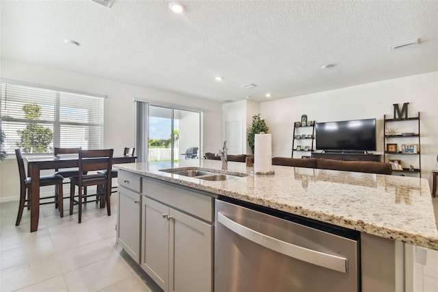 kitchen with gray cabinetry, sink, a textured ceiling, stainless steel dishwasher, and light stone counters