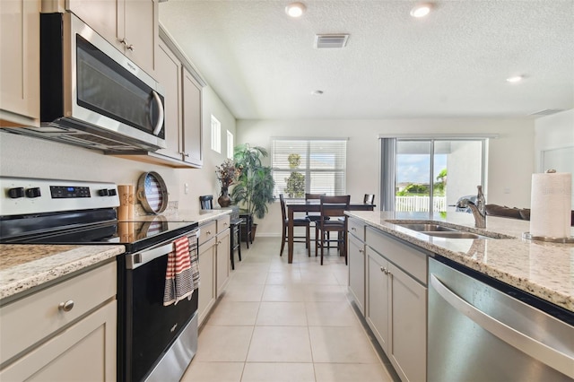 kitchen featuring sink, light stone countertops, stainless steel appliances, and light tile patterned floors