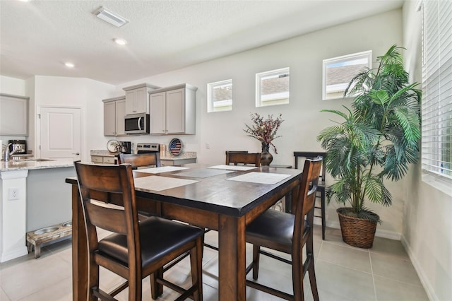 tiled dining room featuring a wealth of natural light, sink, and a textured ceiling