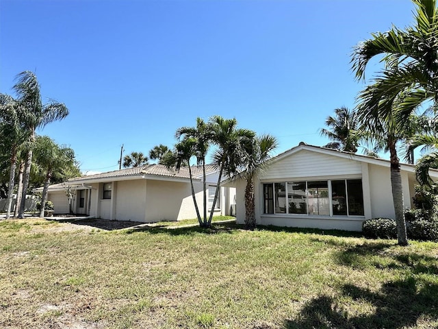 back of property with a yard and a sunroom