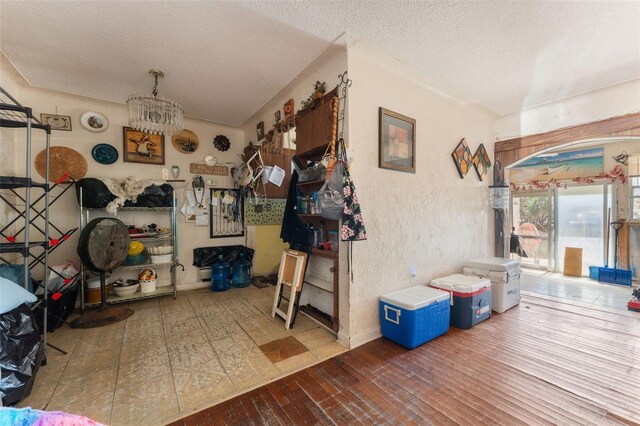 14180 W Parsley Dr, Madeira Beach, FL 33708 - interior space featuring a textured wall, an inviting chandelier, a textured ceiling, and wood-type flooring