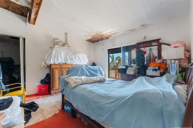 bedroom featuring access to outside, a textured ceiling, beamed ceiling, and carpet flooring