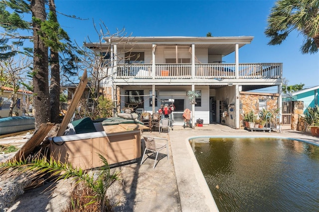 14180 W Parsley Dr, Madeira Beach, FL 33708 - rear view of house with stone siding, a pool, a balcony, and a patio