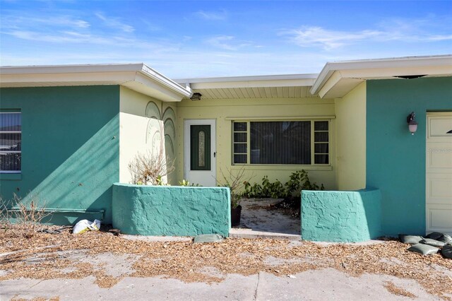 doorway to property with an attached garage and stucco siding