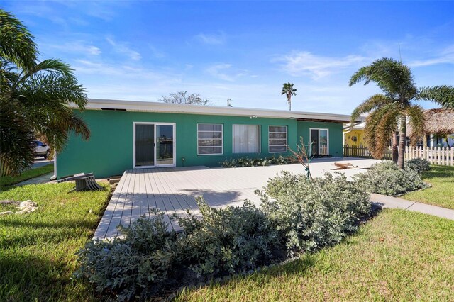 back of property with stucco siding, fence, and a deck