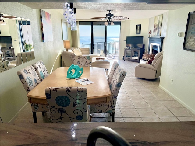 dining room featuring a fireplace, tile patterned flooring, a ceiling fan, and baseboards