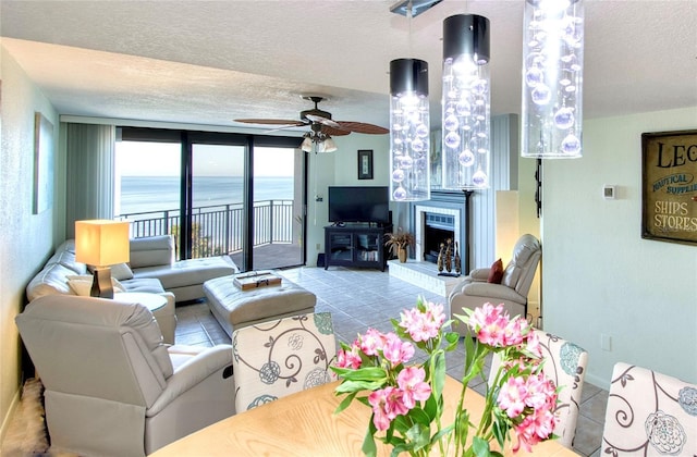 tiled living room featuring ceiling fan, baseboards, a fireplace with raised hearth, and a textured ceiling