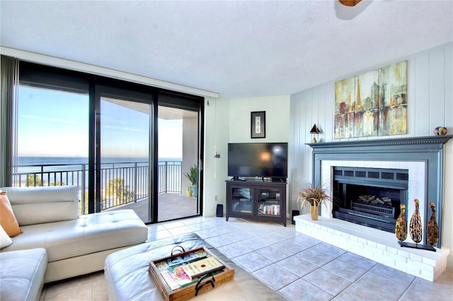 living area with a wall of windows, tile patterned flooring, a brick fireplace, and a textured ceiling