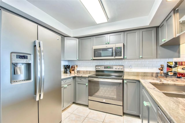 kitchen with gray cabinets, stainless steel appliances, and decorative backsplash