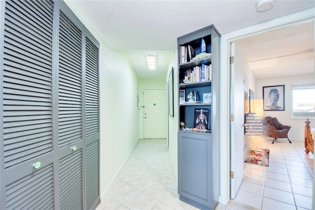 hall featuring a textured ceiling and light tile patterned flooring