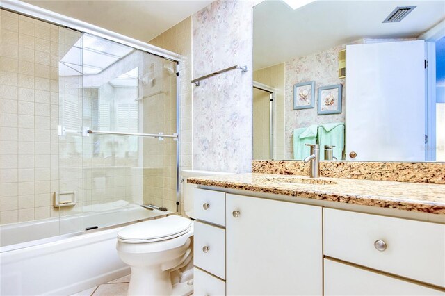 full bathroom with visible vents, toilet, combined bath / shower with glass door, vanity, and tile patterned flooring