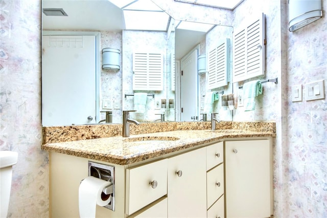 bathroom with double vanity, a sink, and visible vents