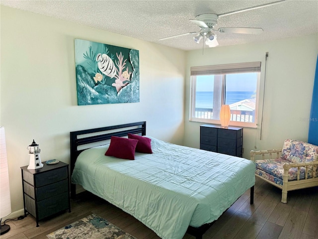 bedroom with a textured ceiling, hardwood / wood-style floors, and a ceiling fan