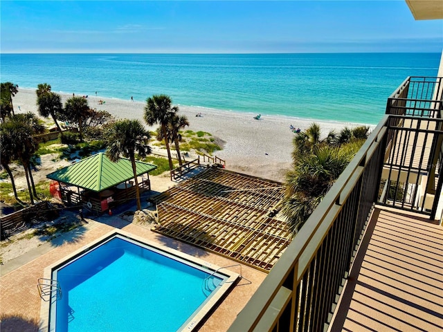 community pool with a gazebo and view of water and beach