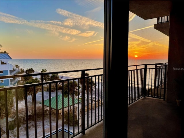 balcony at dusk featuring a water view and view of pool
