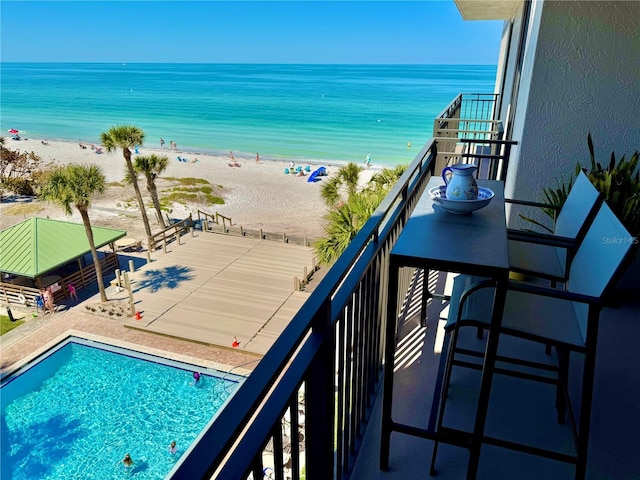 balcony featuring view of water and beach and view of pool