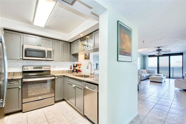kitchen with stainless steel appliances, gray cabinetry, and a sink