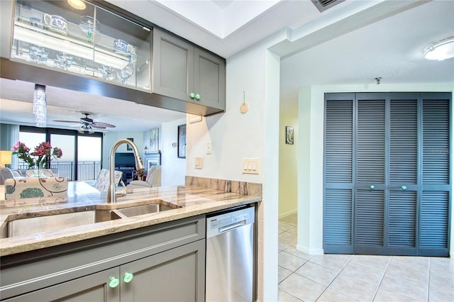 kitchen with dishwasher, gray cabinetry, light tile patterned floors, and light stone counters