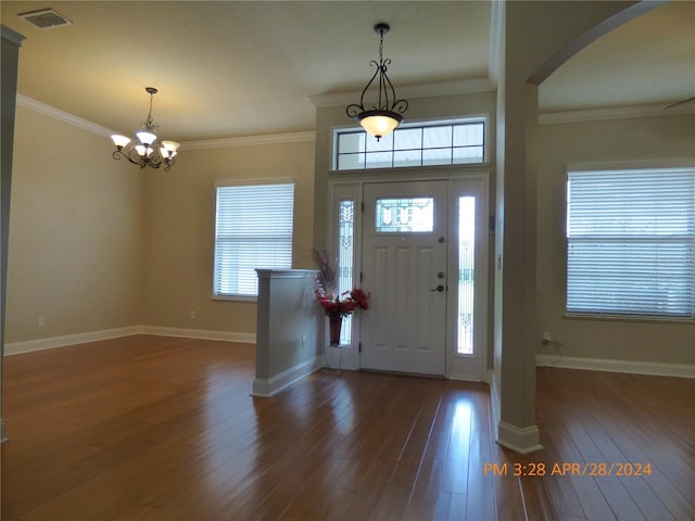 entrance foyer featuring a notable chandelier, ornamental molding, and dark hardwood / wood-style flooring